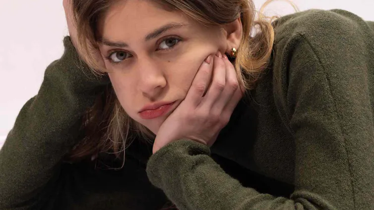 A young woman in a green jumper with long hair
