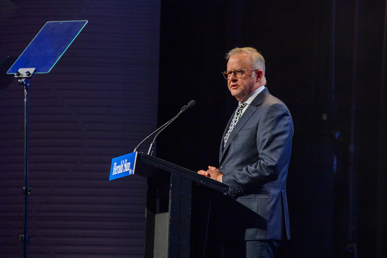 Anthony Albanese stands at a lectern and addresses a crowd