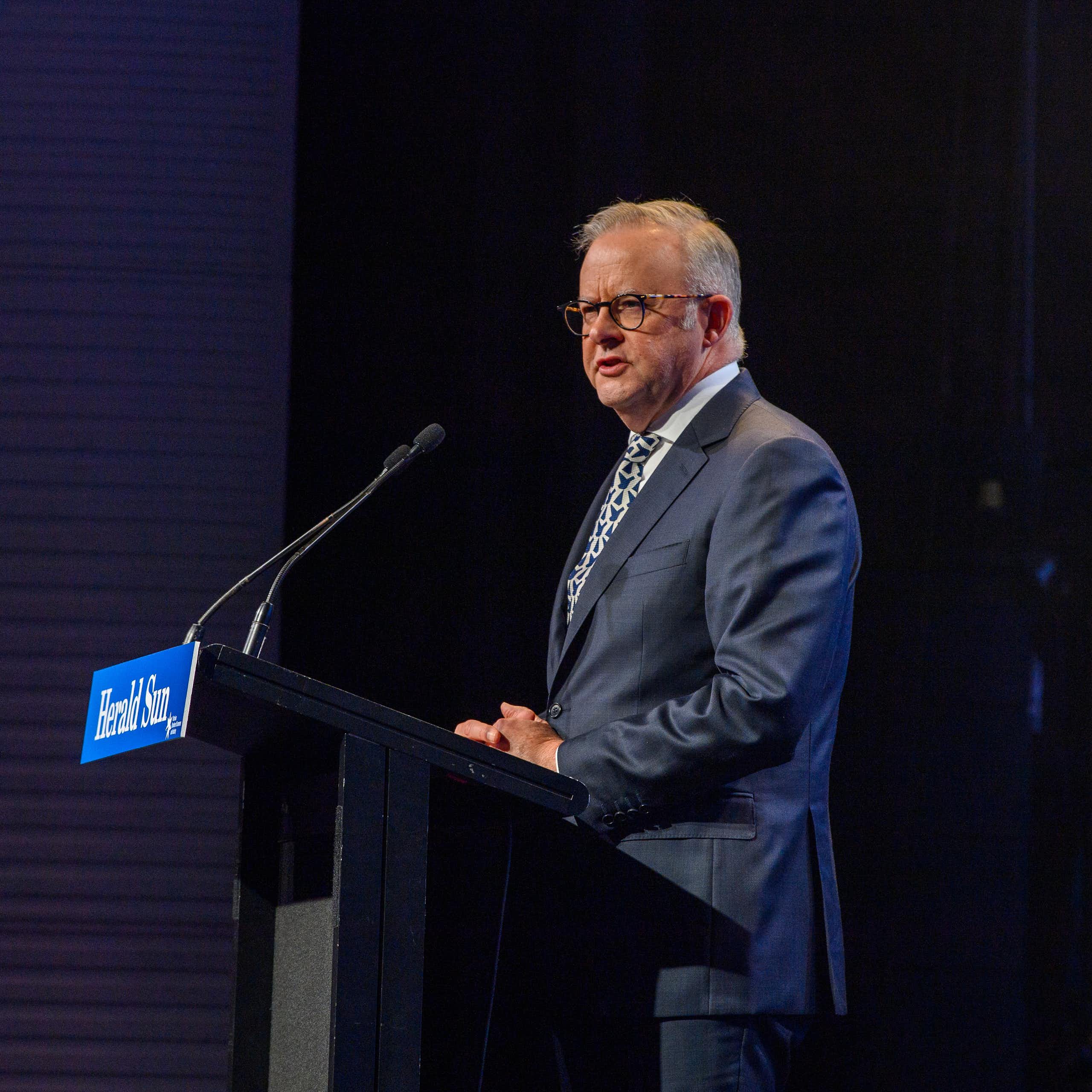 Anthony Albanese stands at a lectern and addresses a crowd