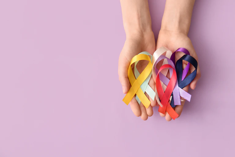 Two hands holding ribbons of various colours representing different cancer charities.