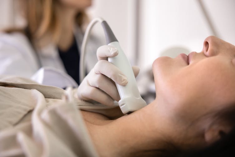 A woman having her neck examined by ultrasound.