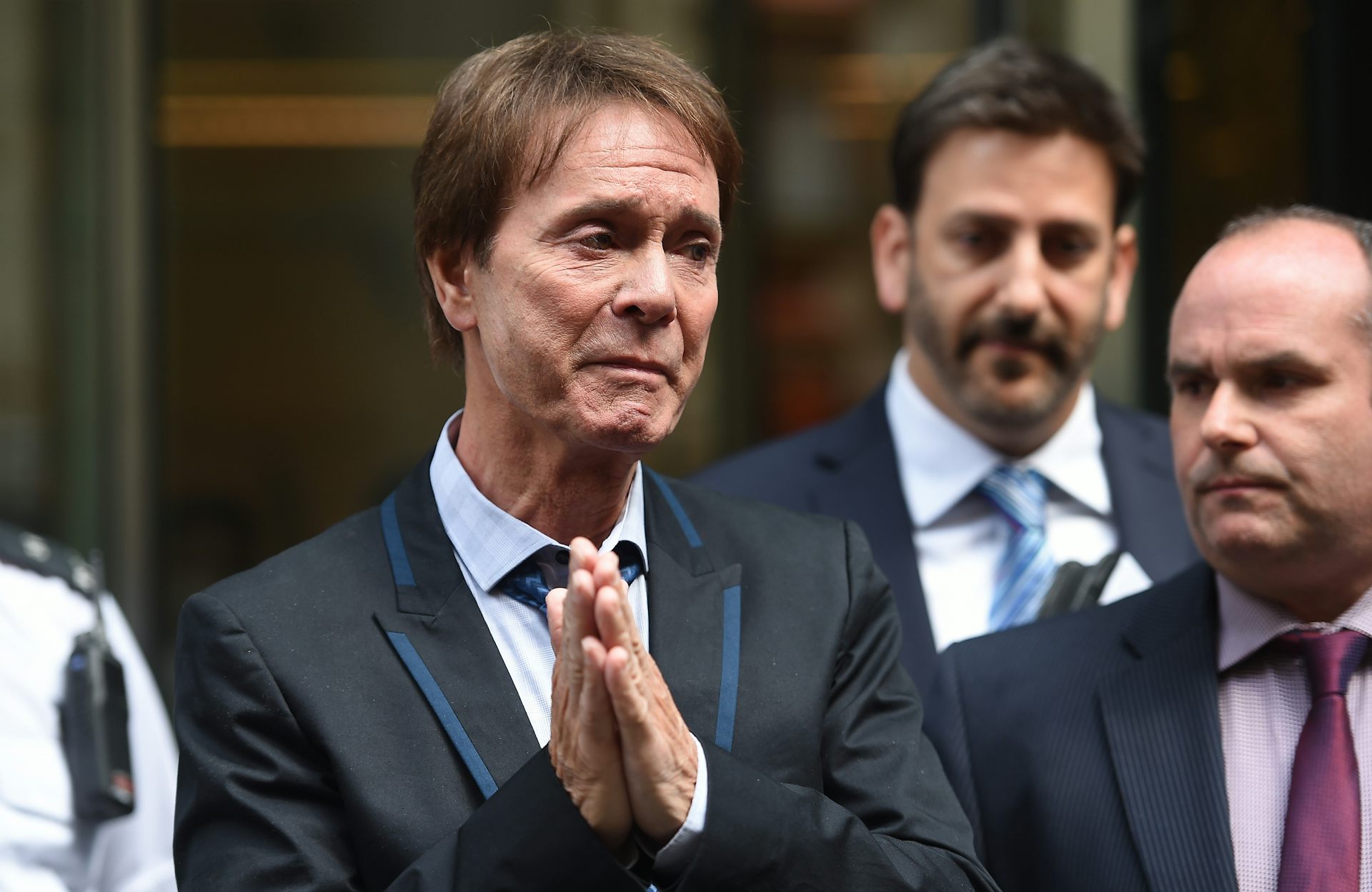 An emotional Richard with his hands clasped together outside the court