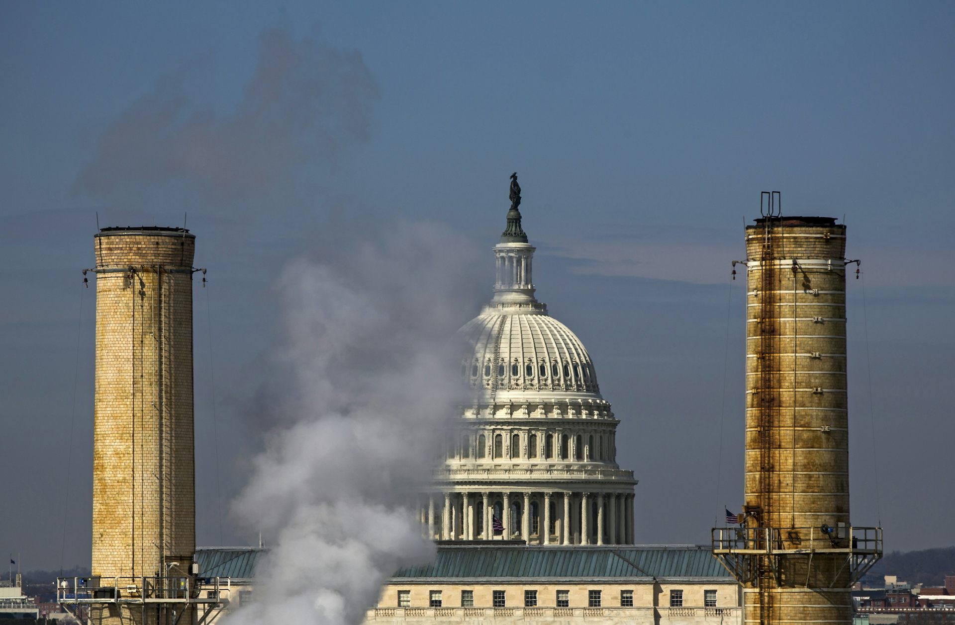 The dome of the US Capitol building seen behind the smokestacks of the Capitol Power Plant.