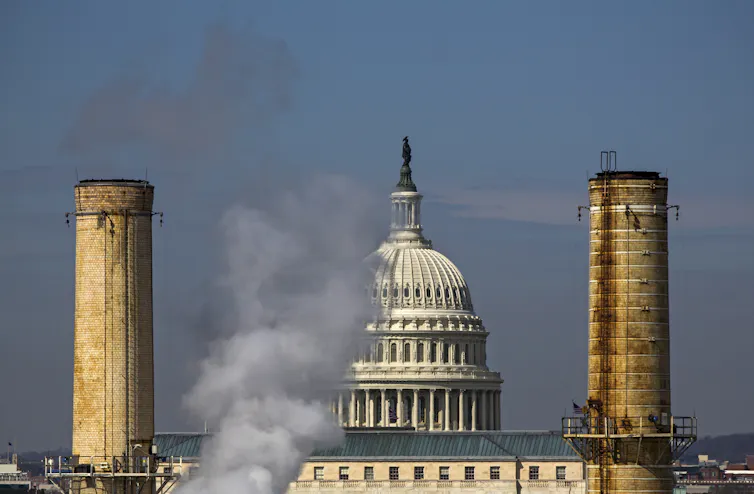The dome of the US Capitol building seen behind the smokestacks of the Capitol Power Plant.