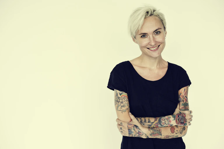 Une femme a les bras découverts et couverts de tatouage.