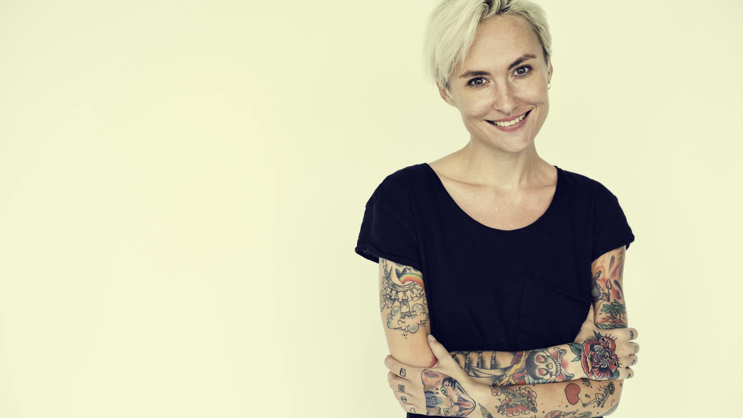 Une femme a les bras découverts et couverts de tatouage.