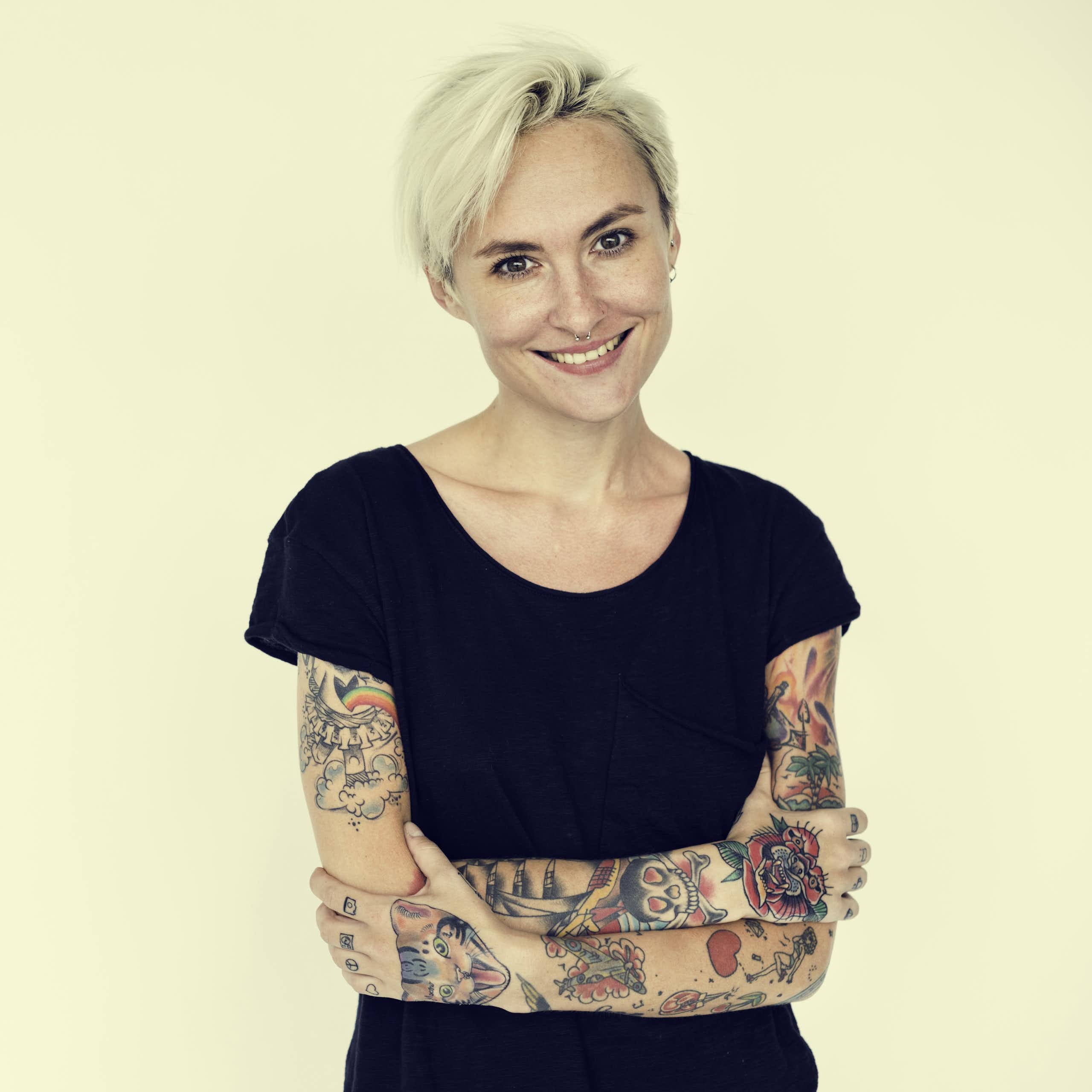 Une femme a les bras découverts et couverts de tatouage.