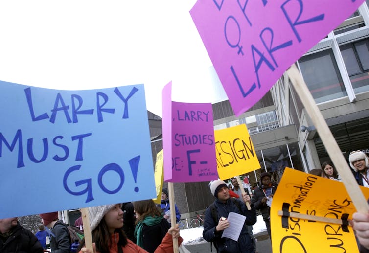 Young women hold signs that say 'Larry Must Go!'