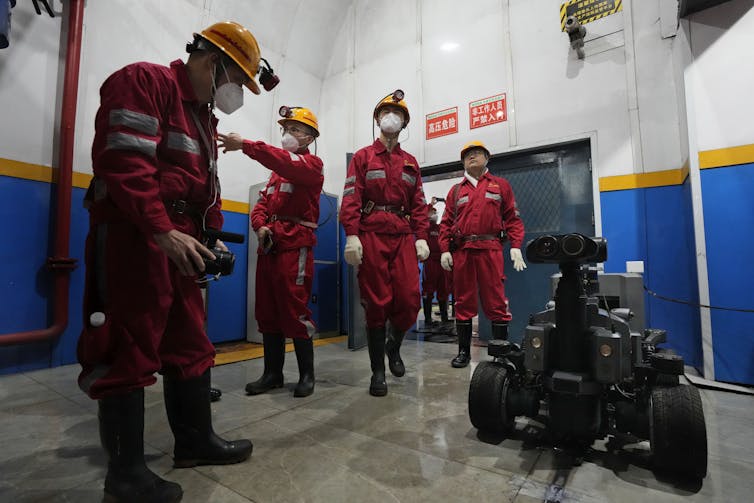 workers stand near a robot