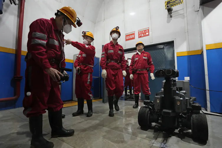 workers stand near a robot