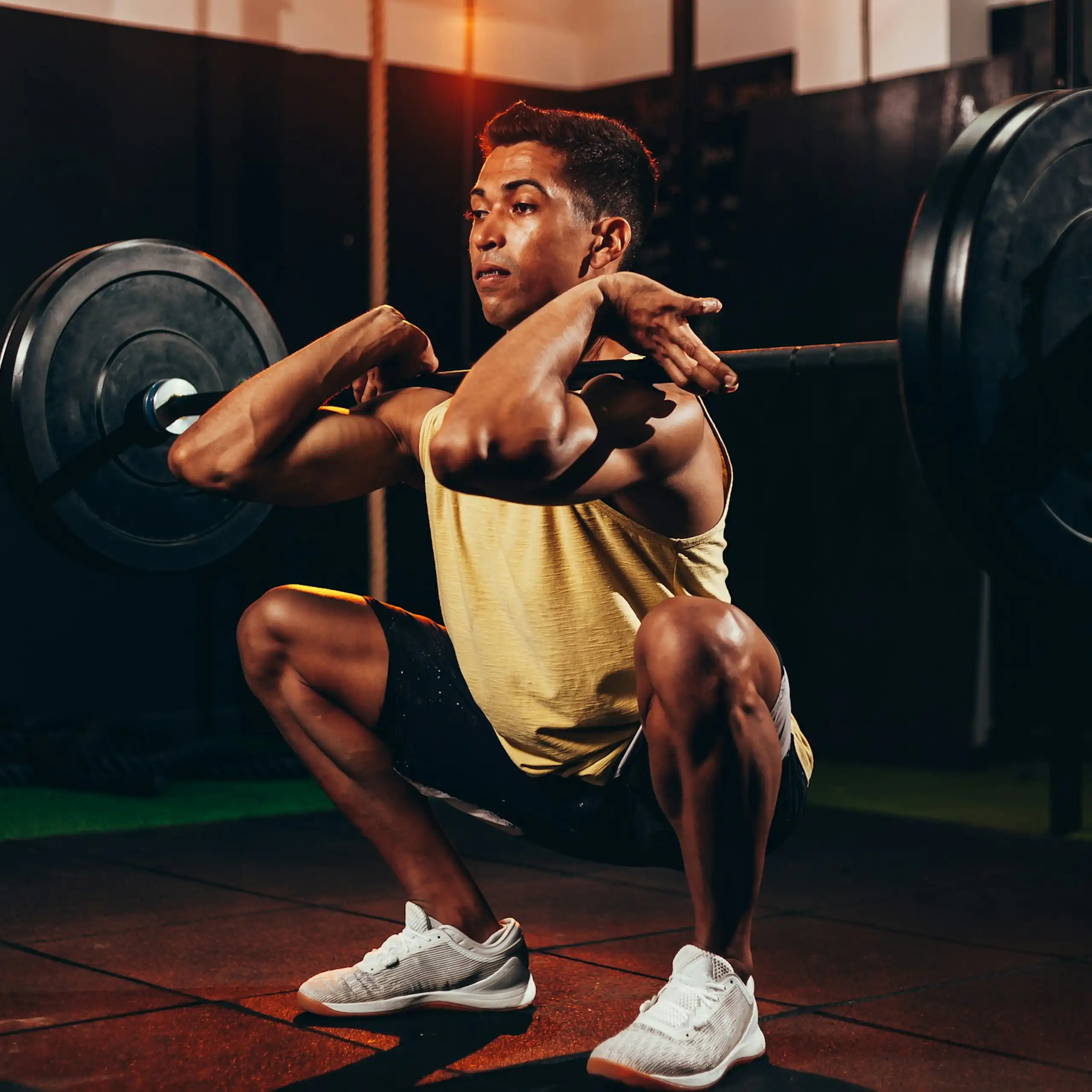 Man squats while lifting heavy weights.