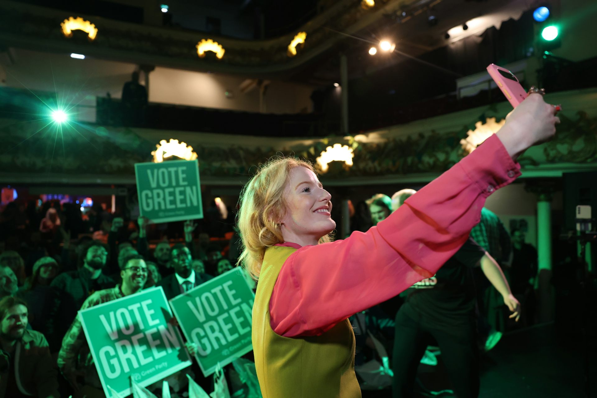 Hannah Spencer takes a selfie in front of a crowd of Vote Green posters