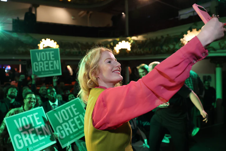 Hannah Spencer takes a selfie in front of a crowd of Vote Green posters