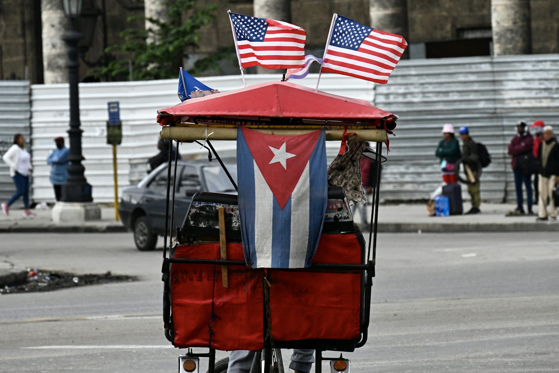 A tricycle has US and Cuban flags attached to it.