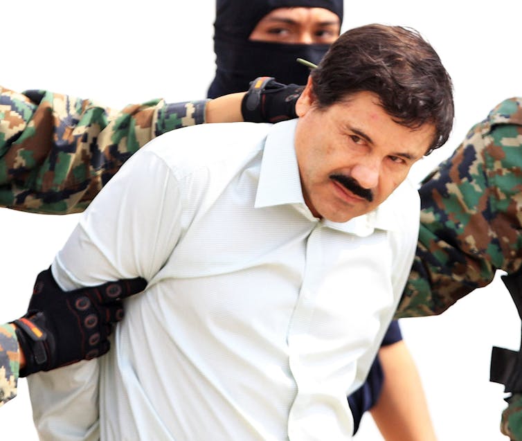 Joaquin 'El Chapo' Guzman being led away by Mexican security agents.