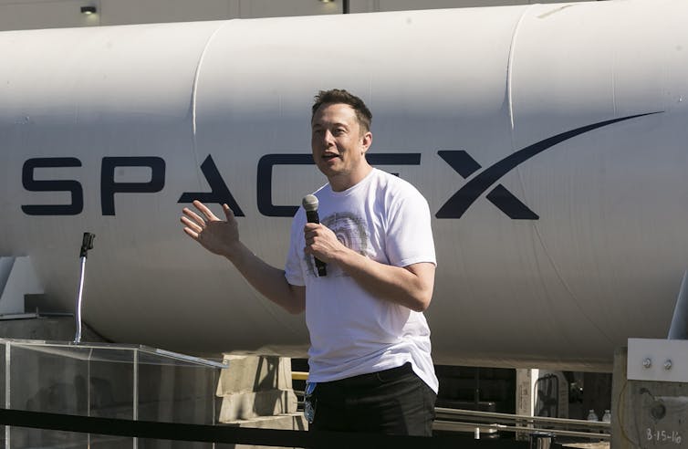 Elon Musk se encuentra frente a un vehículo con una pegatina de
