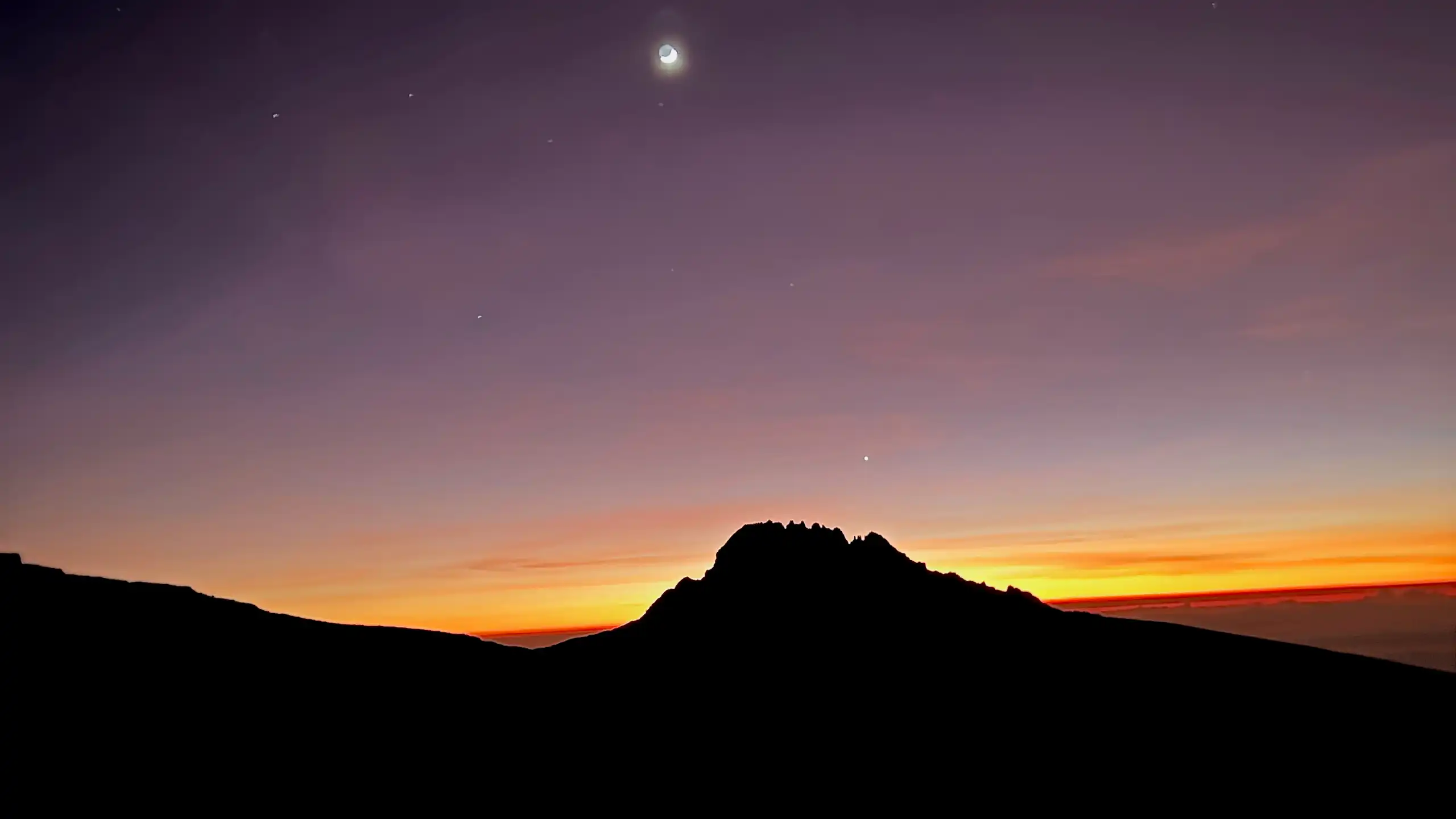 A landscape against a purple sky and breaking dawn
