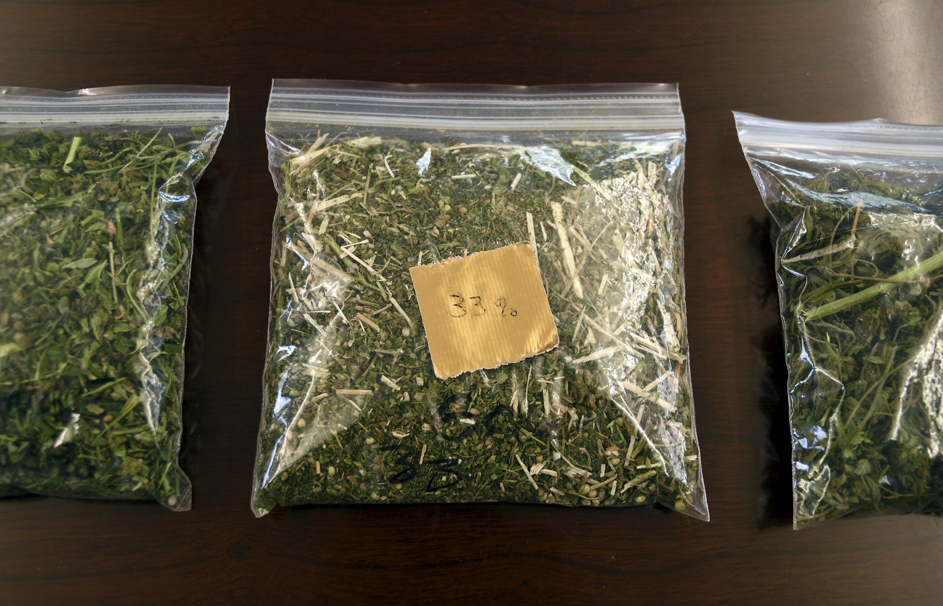 Three bags of cannabis, seized by law enforcement, are on display on a table.