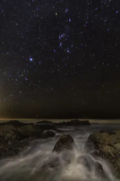 Bright stars visible over a rushing river.