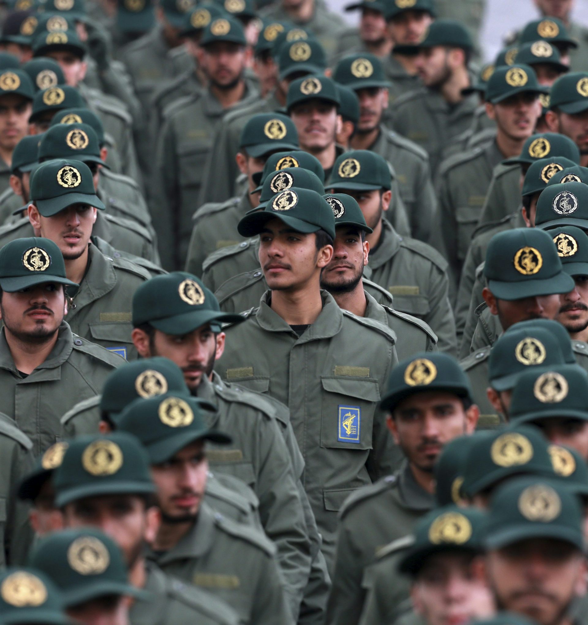 Filas de hombres con uniformes y gorras verdes militares.