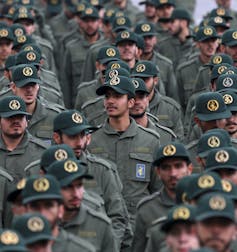 Filas de hombres con uniformes y gorras verdes militares.