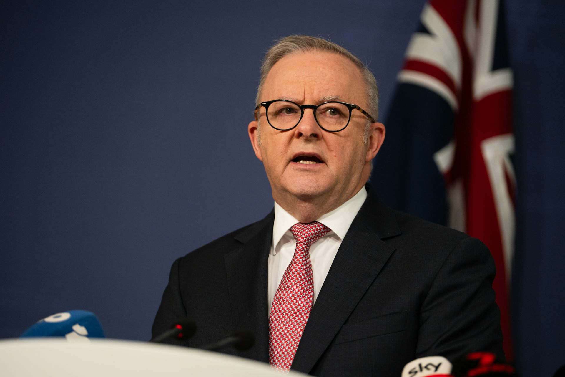 Anthony Albanese speaks in front of an Australian flag