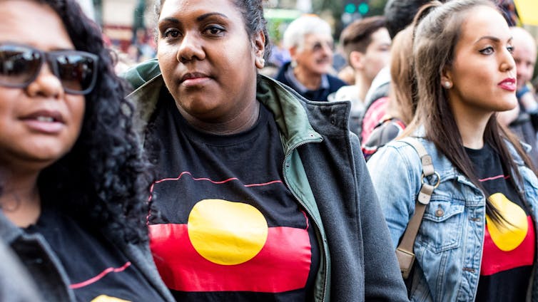 A group of First Nations women wearing t-shirts with the Aboriginal flag on them