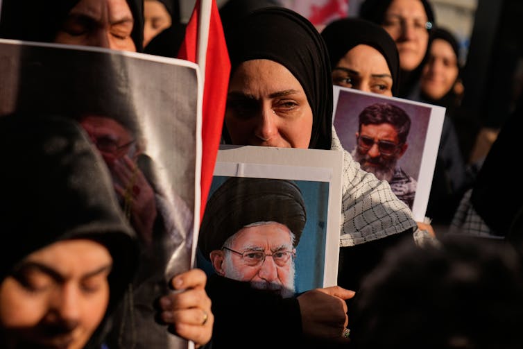 Women in headscarves hold portraits of Ayatollah Ali Khamenei.