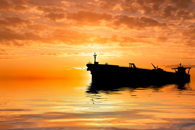 oil tanker silhouetted against an orange sky.
