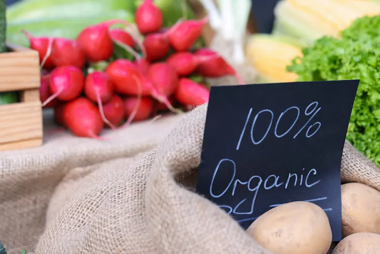 radishes, jute bag of veg, handwritten chalkboard sign says 100% organic