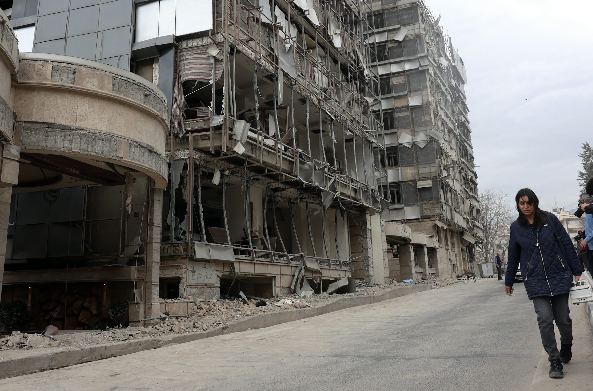People walk past the destroyed Gandhi hospital in Tehran.