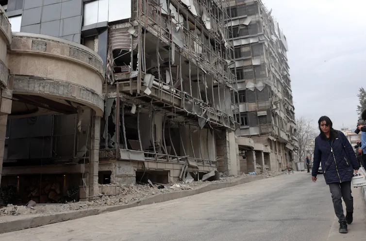 People walk past the destroyed Gandhi hospital in Tehran.