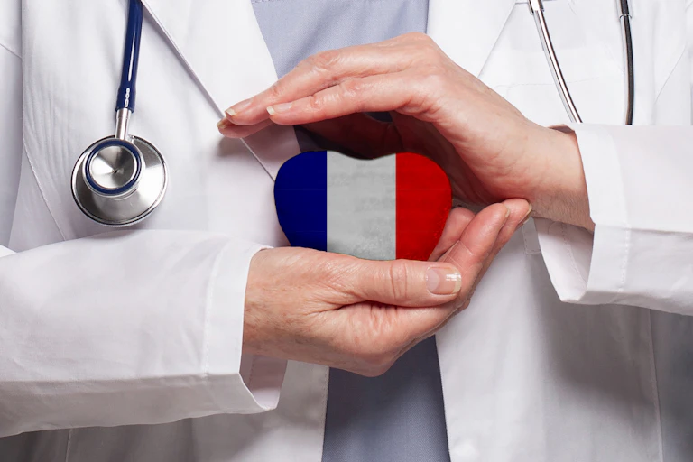 A doctor holds a heart painted in the colours of the French flag with both hands.