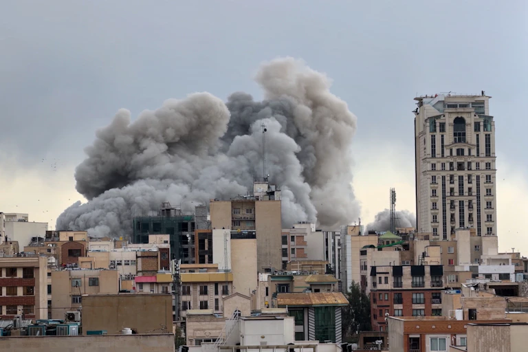 Smoke billows over a city center.