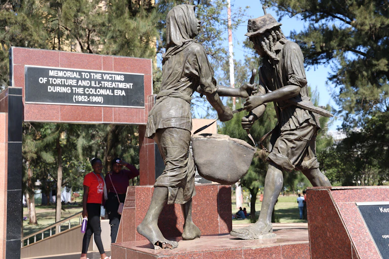 Grey statues of a man and woman holding a basket between them