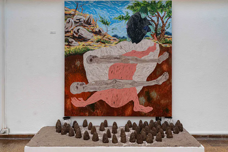 A large painting featuring skeletons behind a semi-circle of clay objects on the ground.
