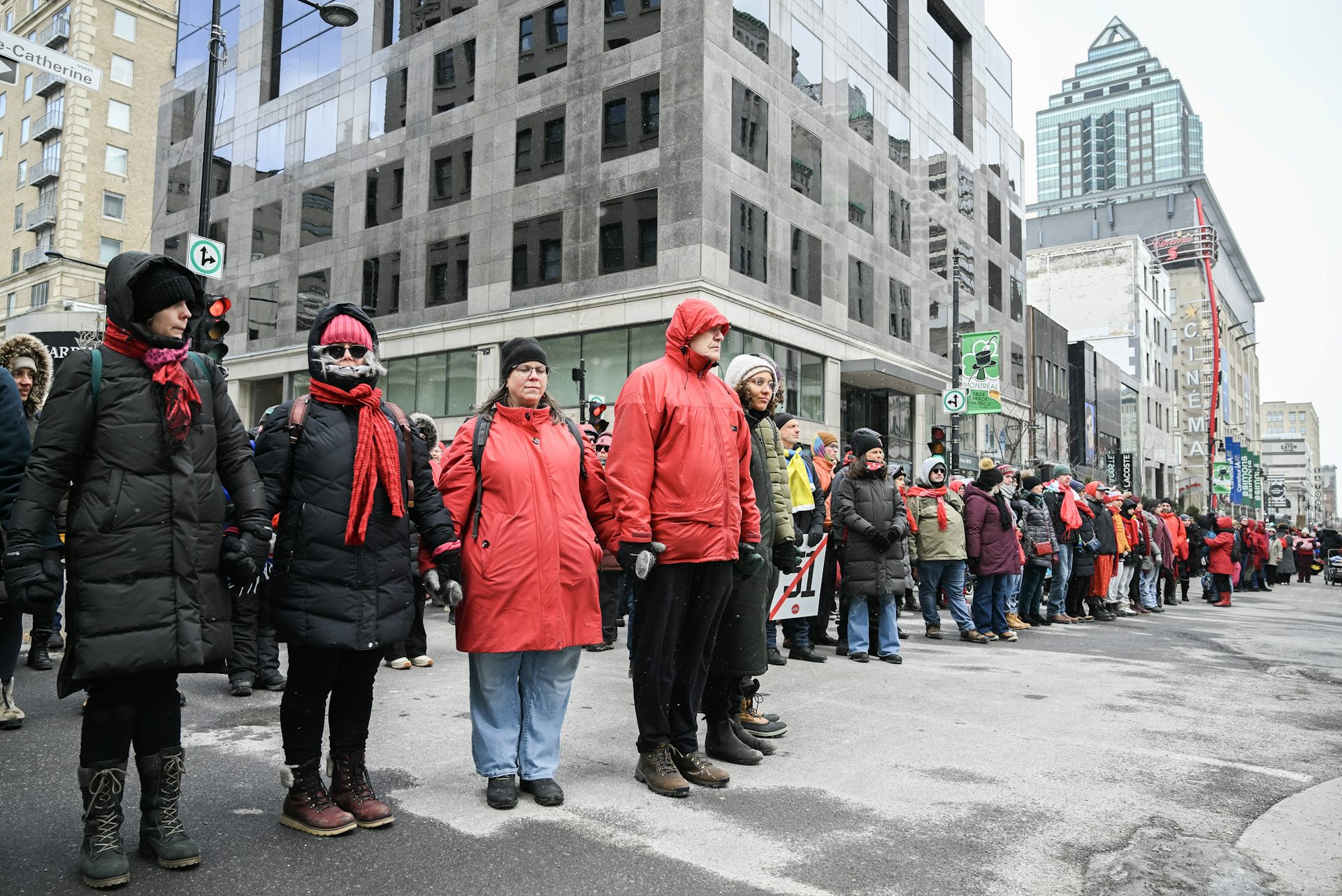 Mujeres vestidas con abrigos de invierno y parkas se dan la mano para formar una cadena humana en una calle del centro.
