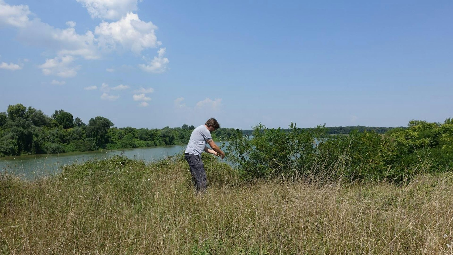 Man stood in a field by a river