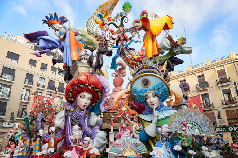 La falla té dos ninots centrals vestits de moro i cristià que es miren amb el dit a la boca, fent-se callar. Molts altres ninots més xicotets, dalt, representen personatges referents a festes populars, música o balls tradicionals.
