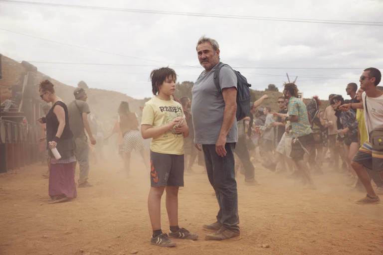 Un hombre y un niño en medio de mucha gente en el desierto.