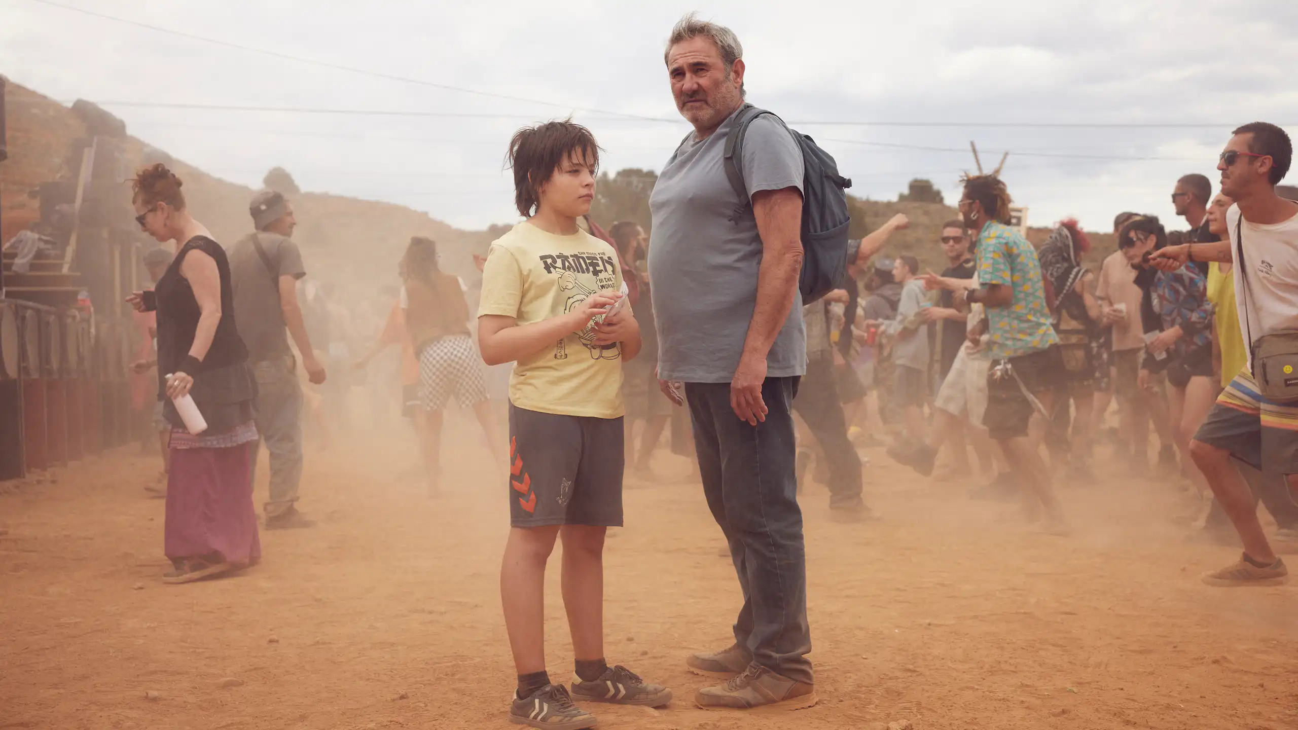 Un hombre y un niño en medio de mucha gente en el desierto.