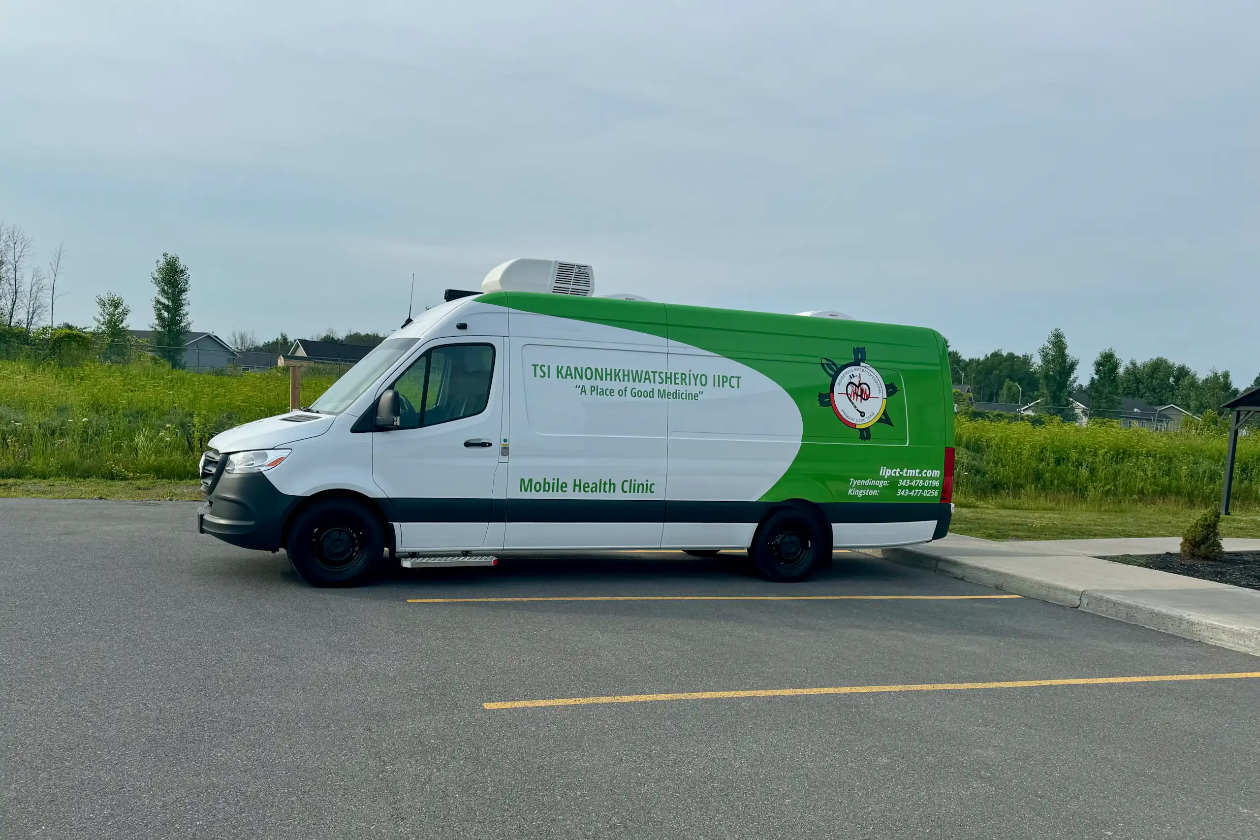 A large green and white van housing a mobile health clinic in a parking lot