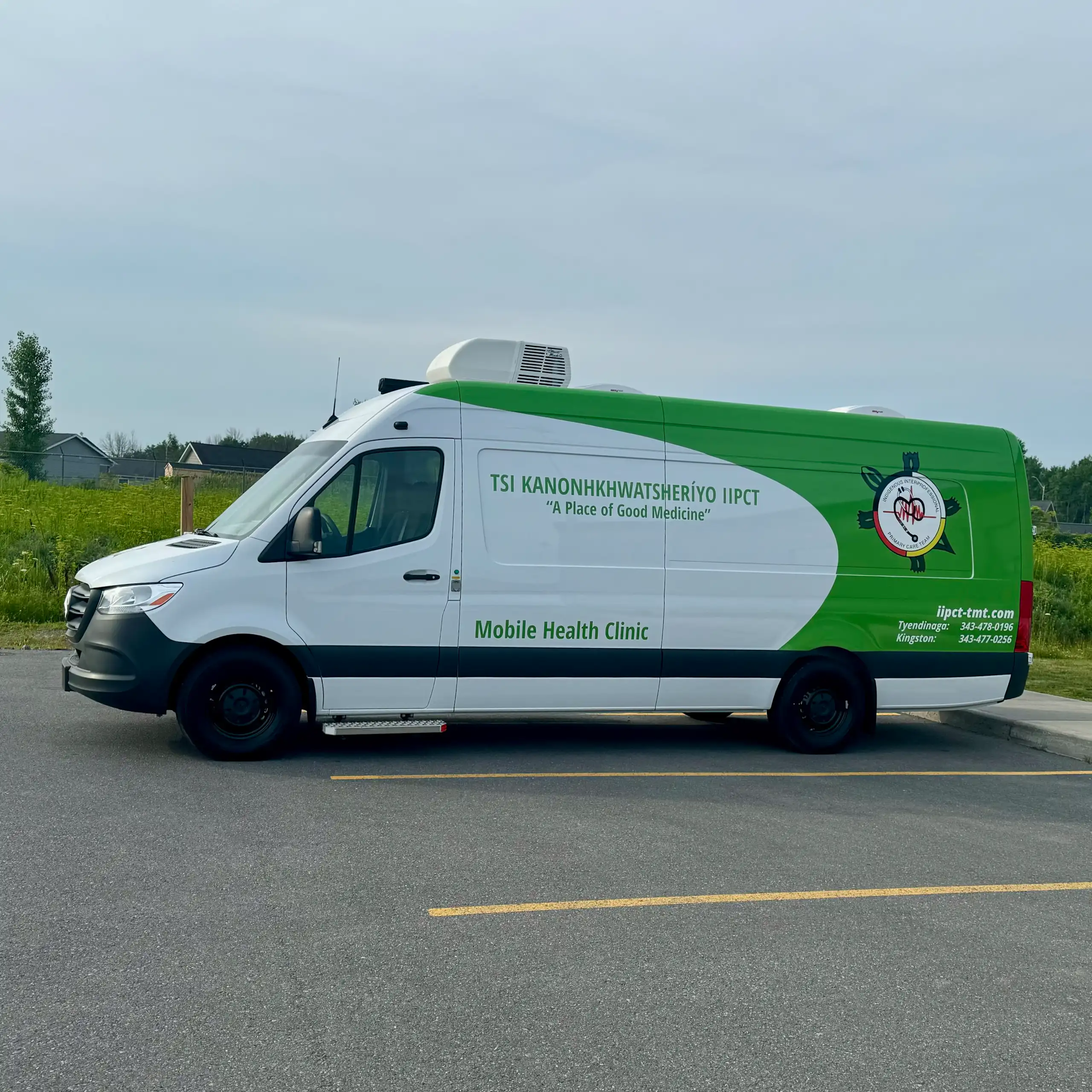 A large green and white van housing a mobile health clinic in a parking lot