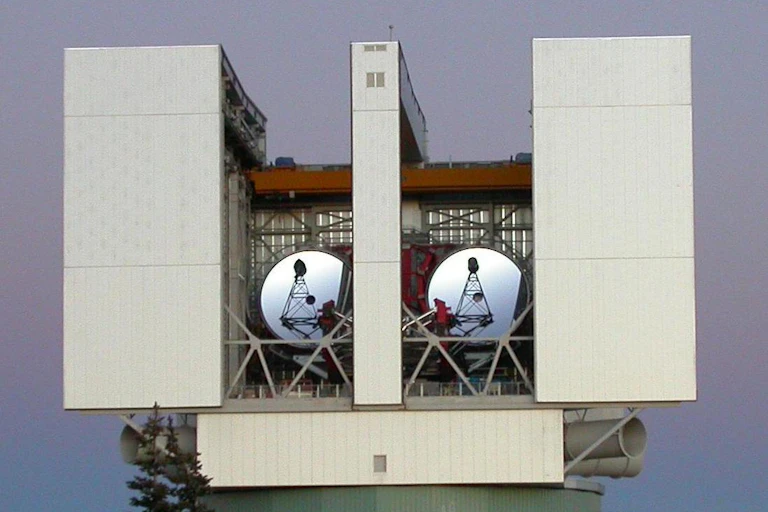 A telescope on a mountaintop set in a box with two antenna disks
