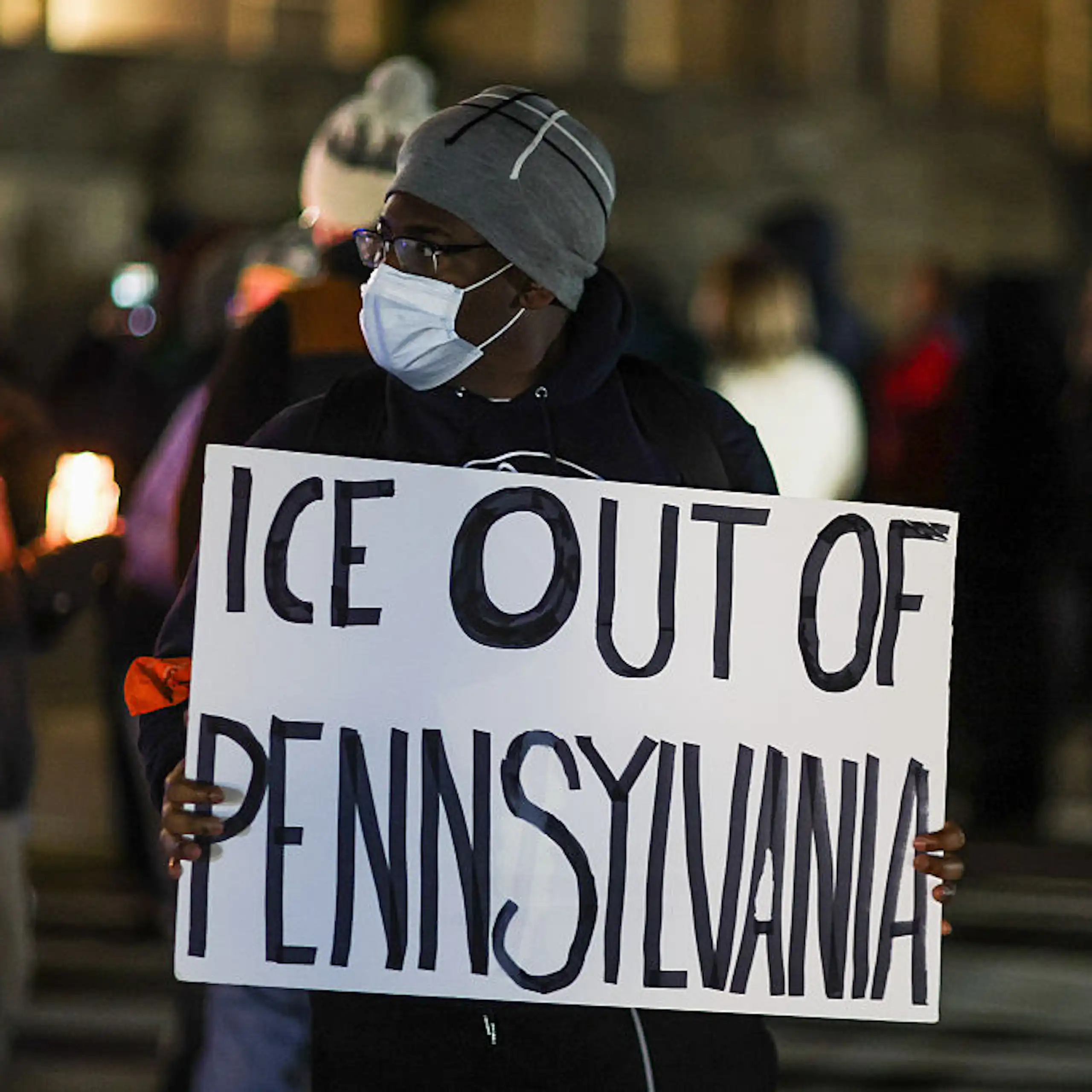 Black woman wearing a medical mask holds sign that reads, "ICE Out Of Pennsylvania."