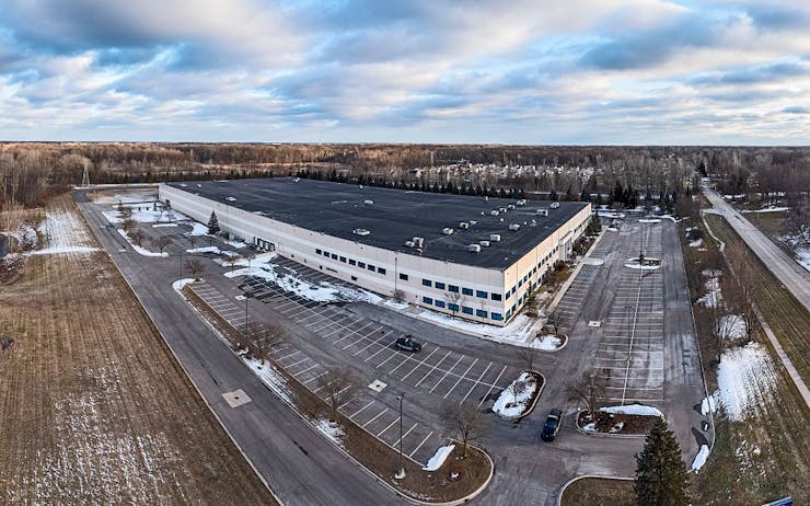 A large warehouse stands in a rural area with snow on the ground.