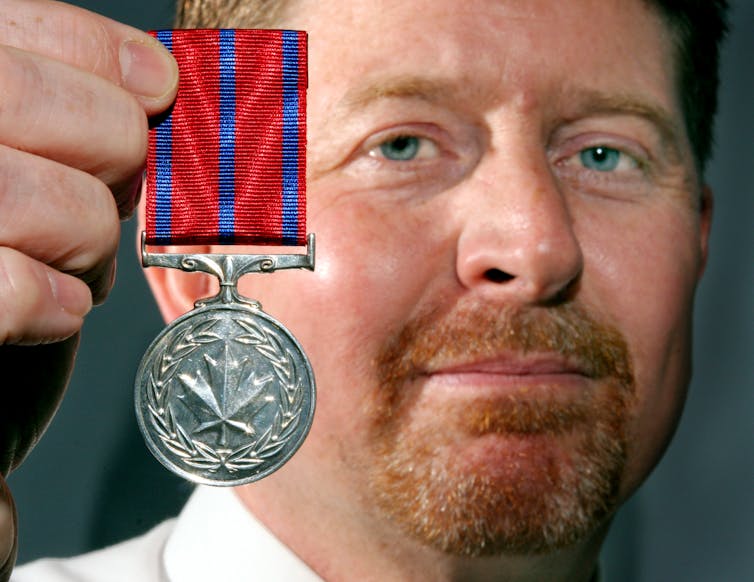 primer plano, de, hombre, tenencia, medalla, con, cinta, en, primer plano