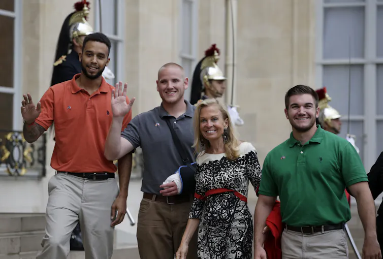 three young men smiling toward camera, walking with a woman