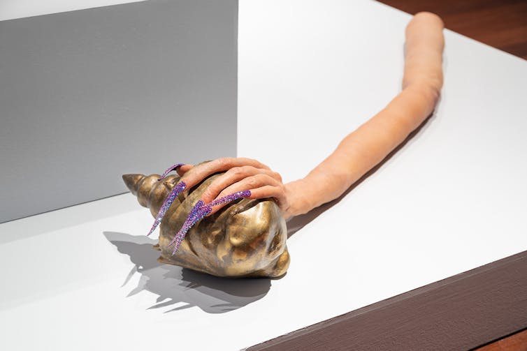 A hand wraps around a gold shell.