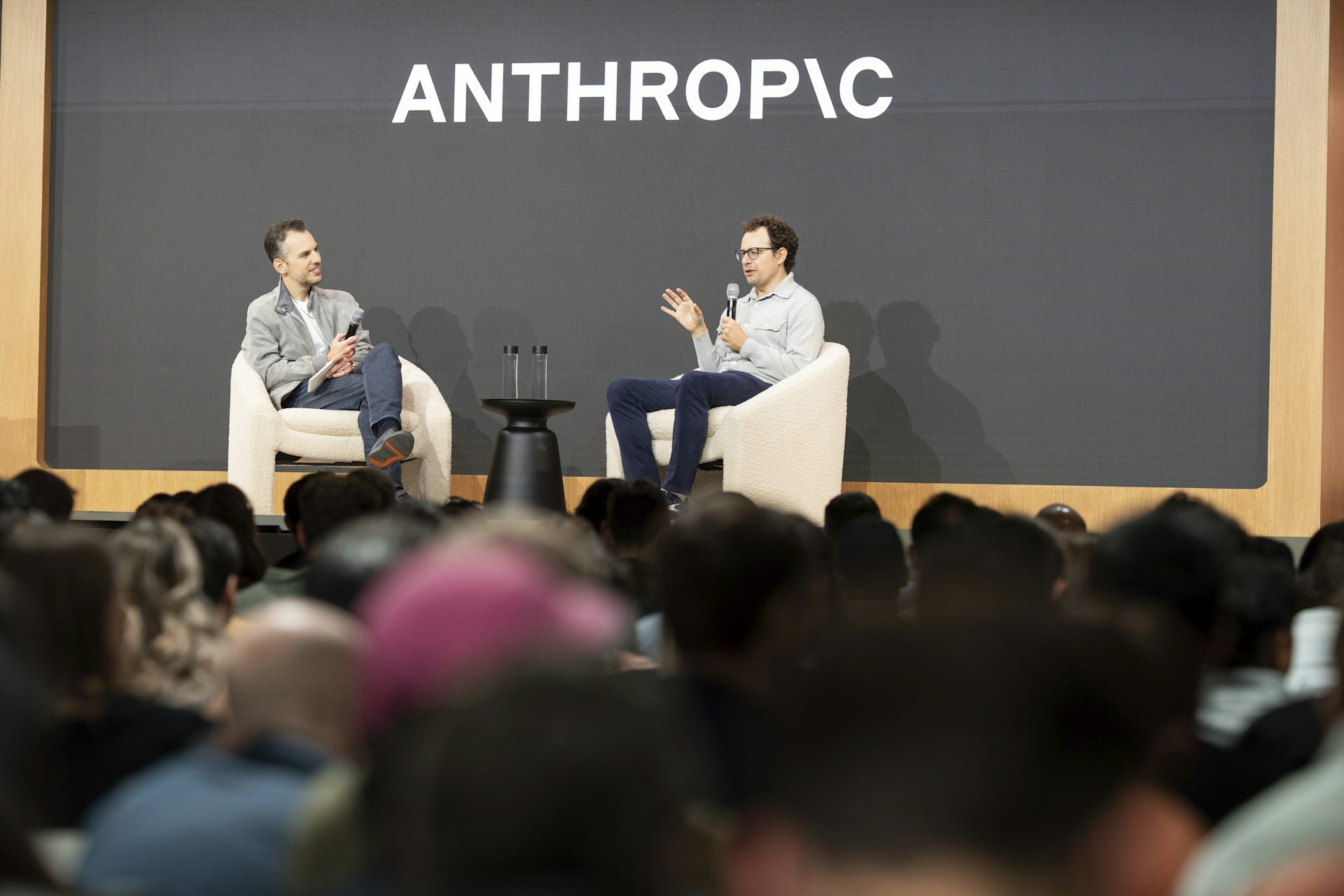 El director ejecutivo de Anthropic, Dario Amodei, y el director de productos, Mike Krieger, hablan en el escenario frente al logotipo de Anthropic.